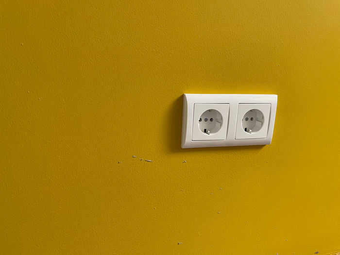 Close-up of telephone mounted on yellow wall