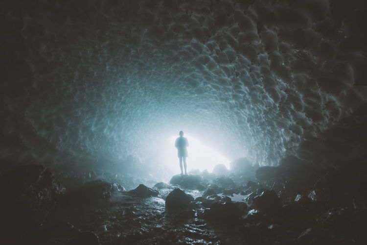 Silhouette woman standing in ice cave