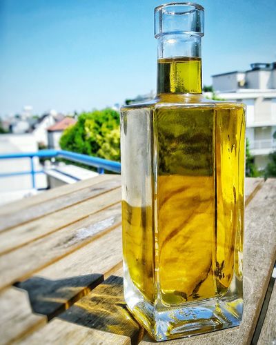 Close-up of olive oil in glass bottle on wooden table at building terrace