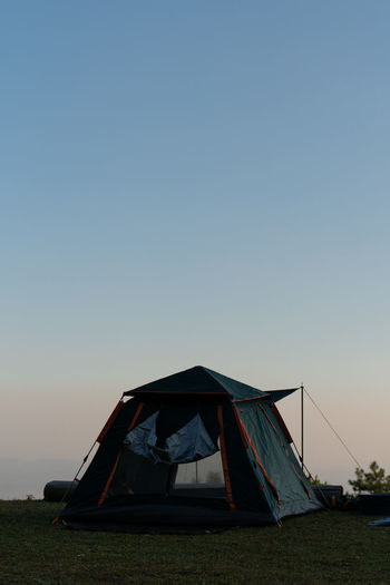Tent on field against clear sky at sunset