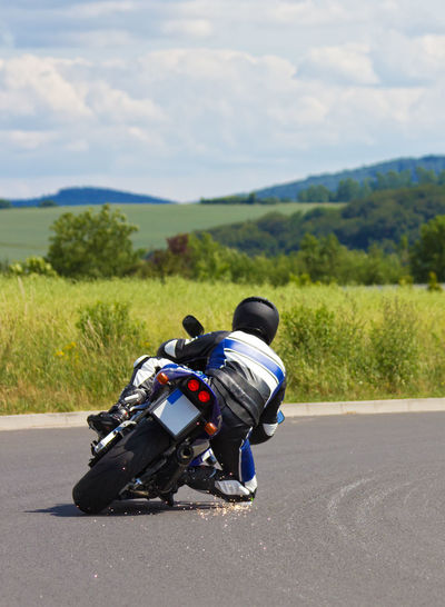 Man riding motorcycle on road against sky