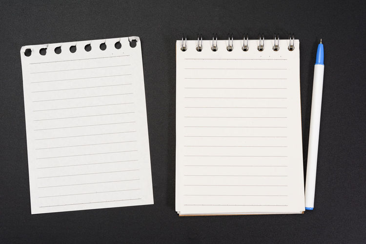 Notebook with white sheets in a line on a black background, close up