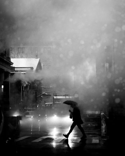 Man on wet street against buildings in city