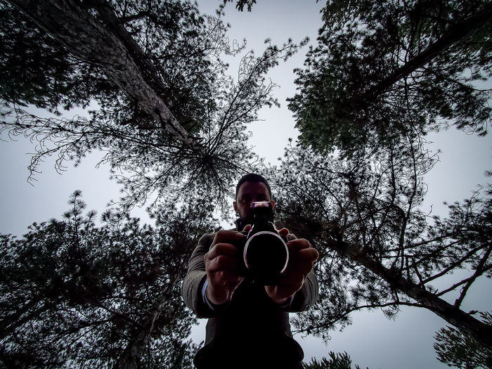 Low angle view of man photographing against sky