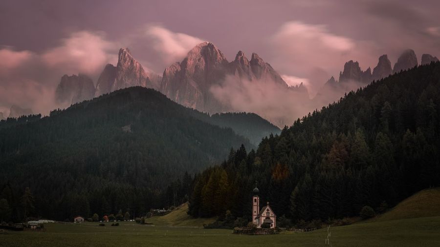 Church on land against mountains at sunset