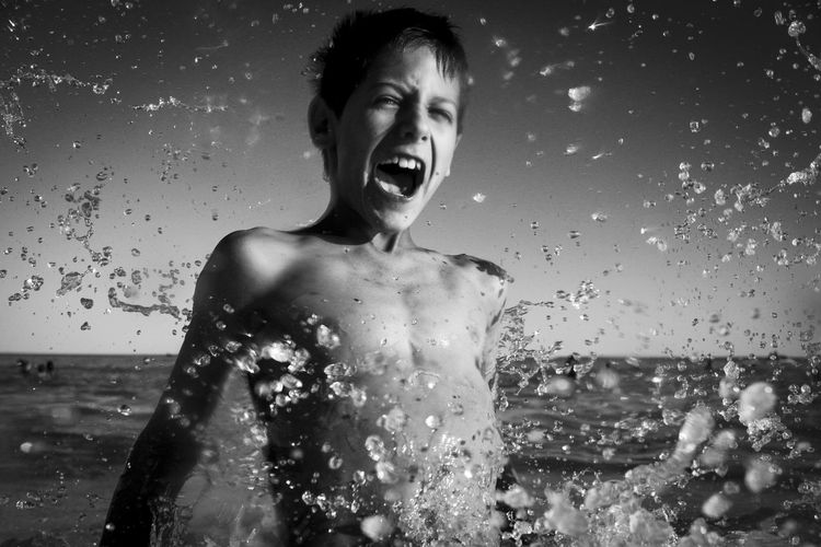 Portrait of shirtless boy splashing water
