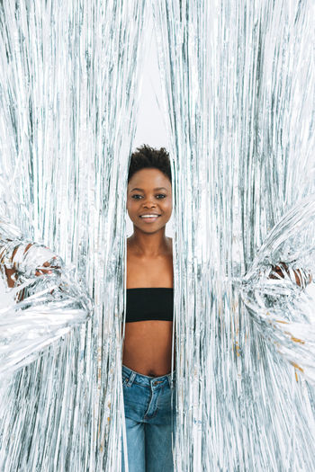 Portrait of happy young african american woman in black top on sparkly silver background, party time