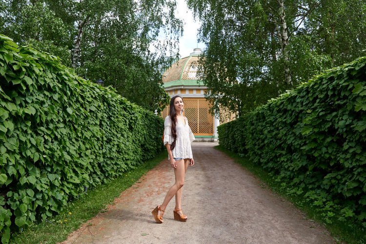 Full length portrait of woman standing on footpath amidst trees