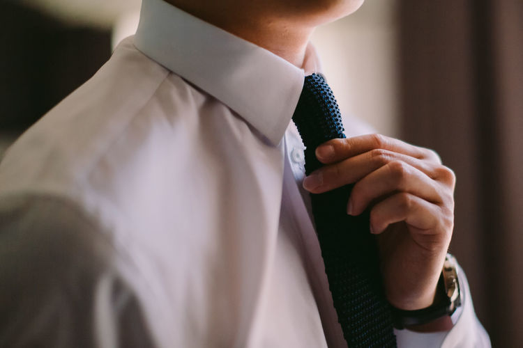Midsection of man holding necktie