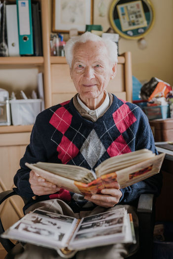 Portrait of senior man looking at photo album at home