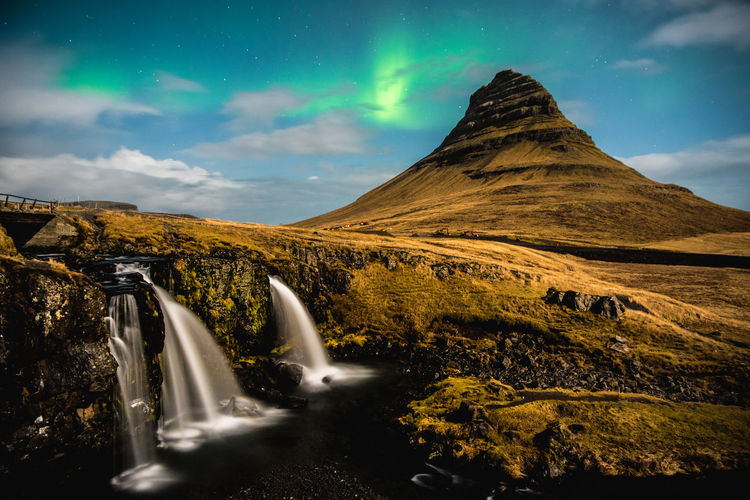 Scenic view of waterfall against sky with aurora borealis