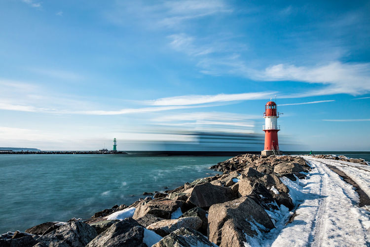 Lighthouse by sea against sky