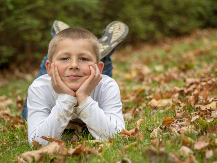 Portrait of cute boy lying on grass during autumn