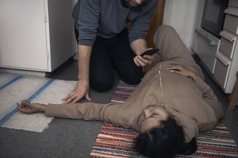Man calling for ambulance for unconscious woman in medical shock