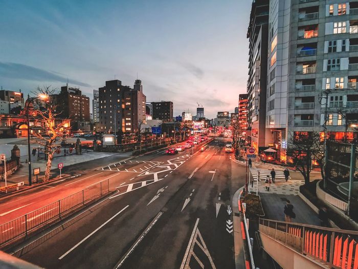 Light trails on city street amidst buildings against sky