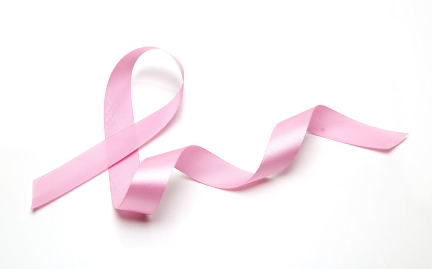 Close-up of breast cancer awareness ribbon over white background