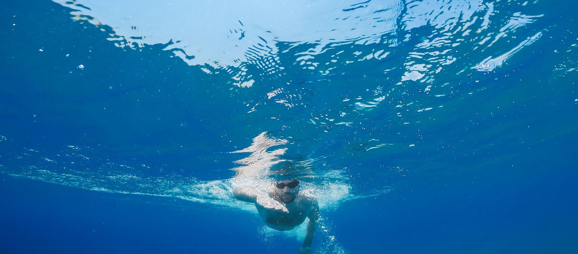 Boy swims freestyle in the open ocean.
