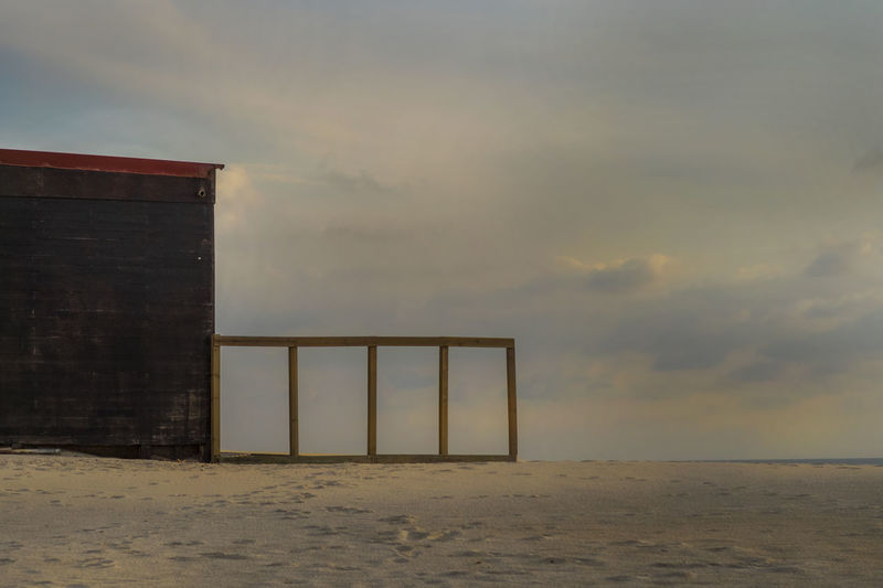 Built structure on beach against sky during sunset