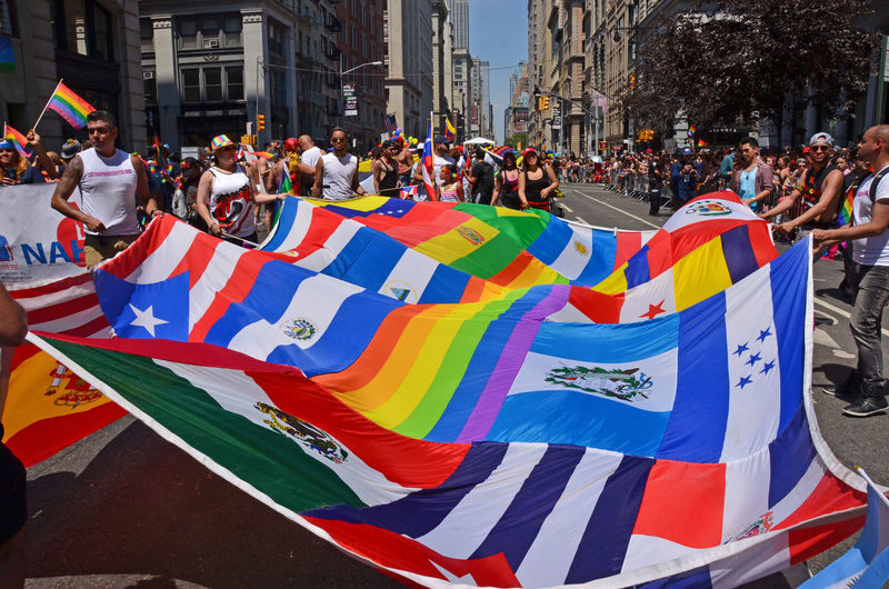 People holding flags and walking during gay pride parade on street