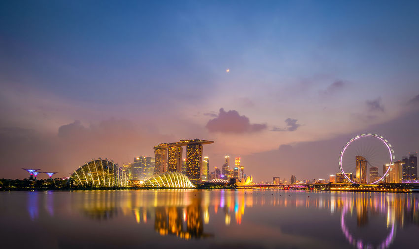 Illuminated marina bay sands at dusk against cloudy sky