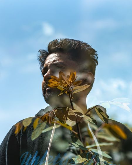 Low angle view of person on flowering plant against sky