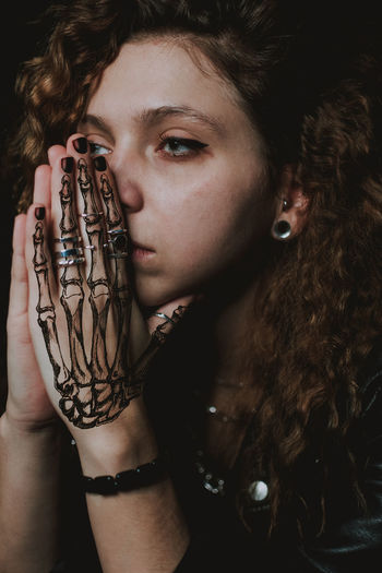 Close-up of young woman looking away with tattoo on hand