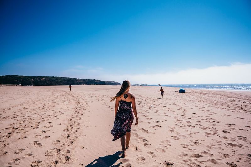 Rear view of woman walking at beach