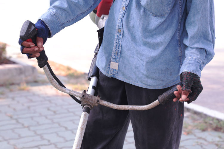 Midsection of man holding metal