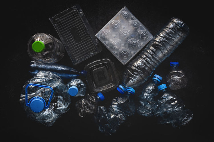 Top view of plastic bottles and boxes arranged on dark background surface
