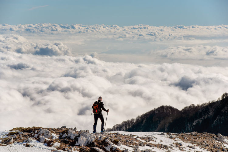 Man standing on land against cloudscape during winter