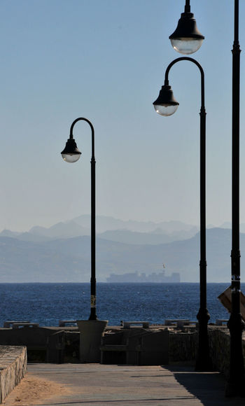 Street light by sea against sky
