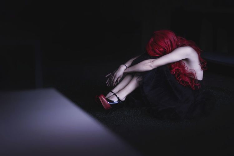 Depressed redhead woman sitting in darkroom