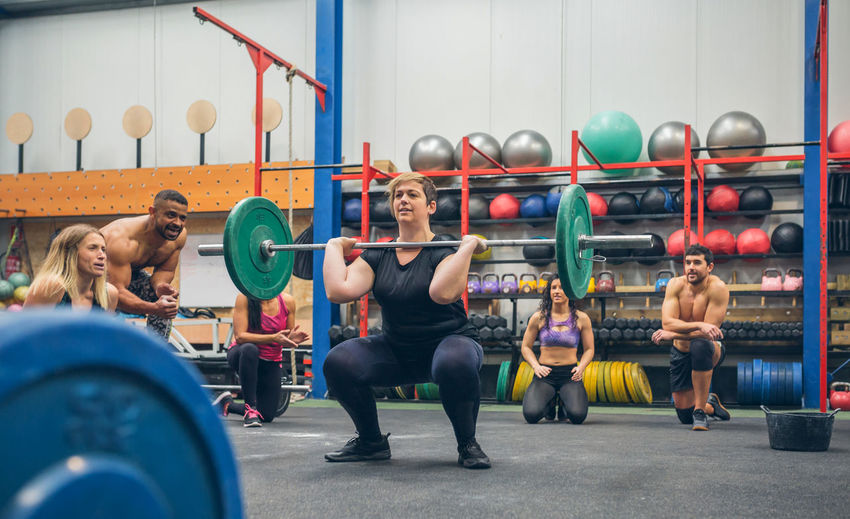 Woman weightlifting while her gym mates cheering her on