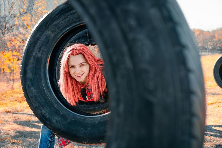 Young woman with colorful hair playing on tire at playground