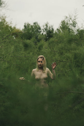 Young naked woman standing in forest