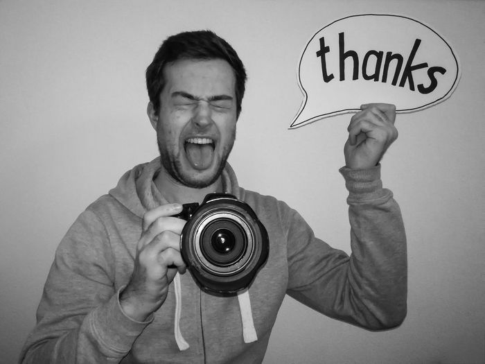 Man holding speech bubble with thanks text while photographing by white background