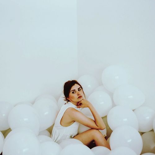 Portrait of young woman sitting on balloons
