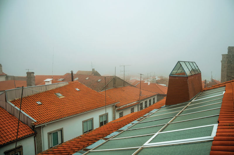 Shingles in roof on top of building, with glass skylight and morning mist at guarda, portugal.