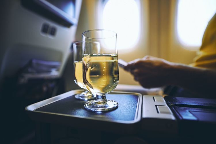 Dring during flight. two drinking glasses of sparkling wine against airplane window.
