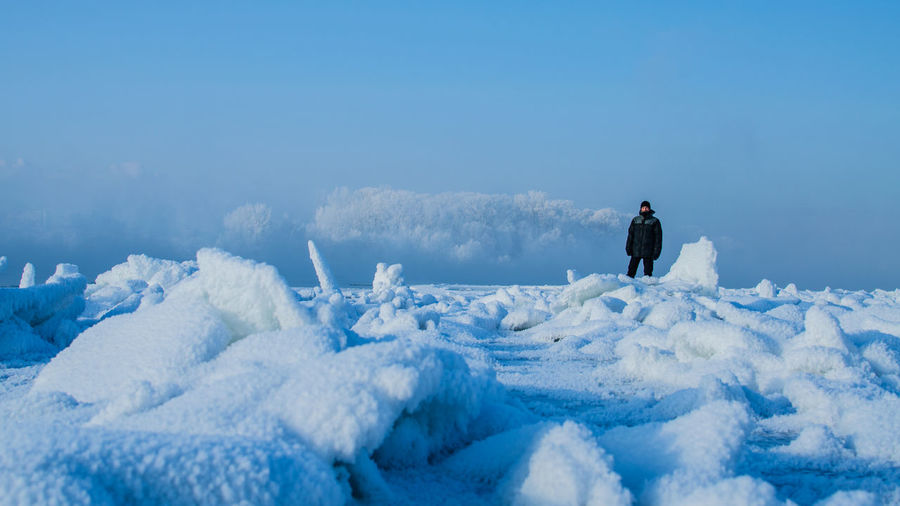 Man standing on snow against blue sky