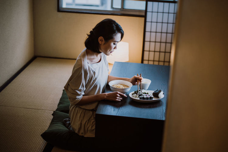 Beautiful woman eating food sitting at home