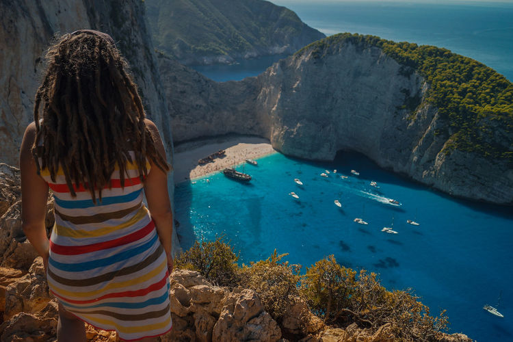 Rear view of woman with dreadlocks looking at sea on mountain