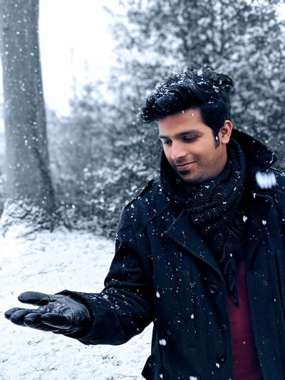 Smiling man standing outdoors during snow fall