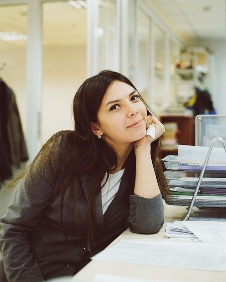 Portrait of young woman looking away while sitting on table