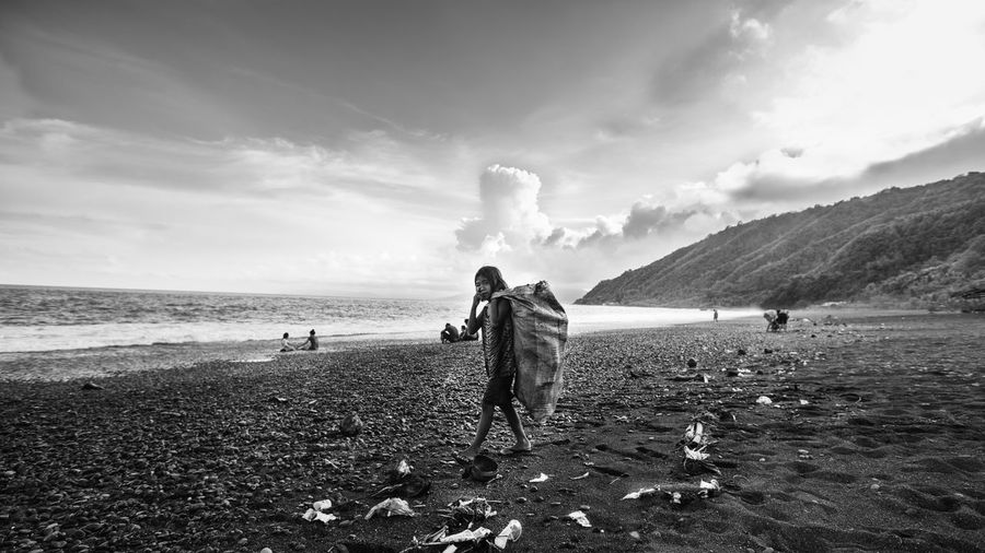 Boy standing on beach against sky