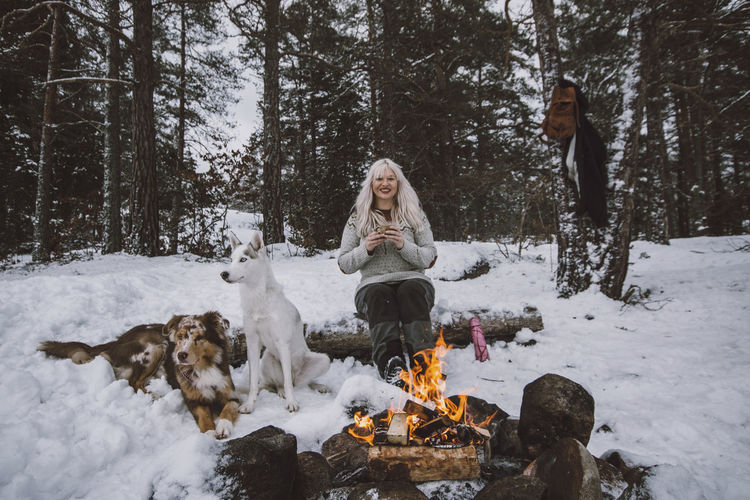 Woman sitting near log fire at winter