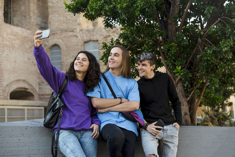 Young diverse friends taking selfie with a mobile phone outdoors.