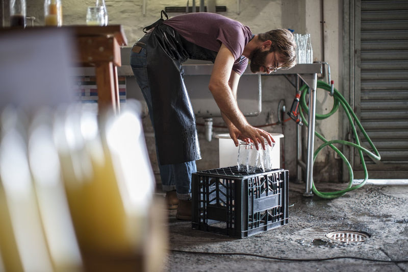 Man placing clean empty glass bottles on crate