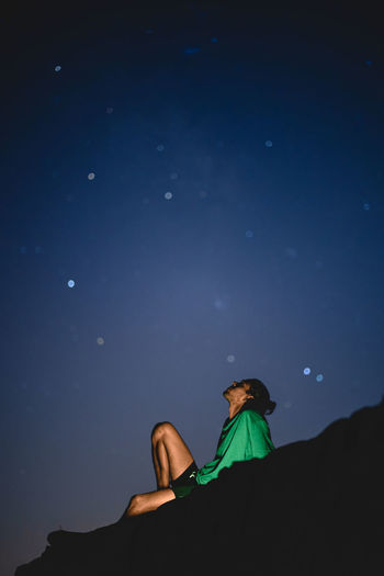 Low angle view of man sitting against night sky