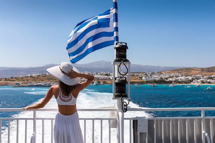 Rear view of young woman looking at view while traveling in ferry against clear sky